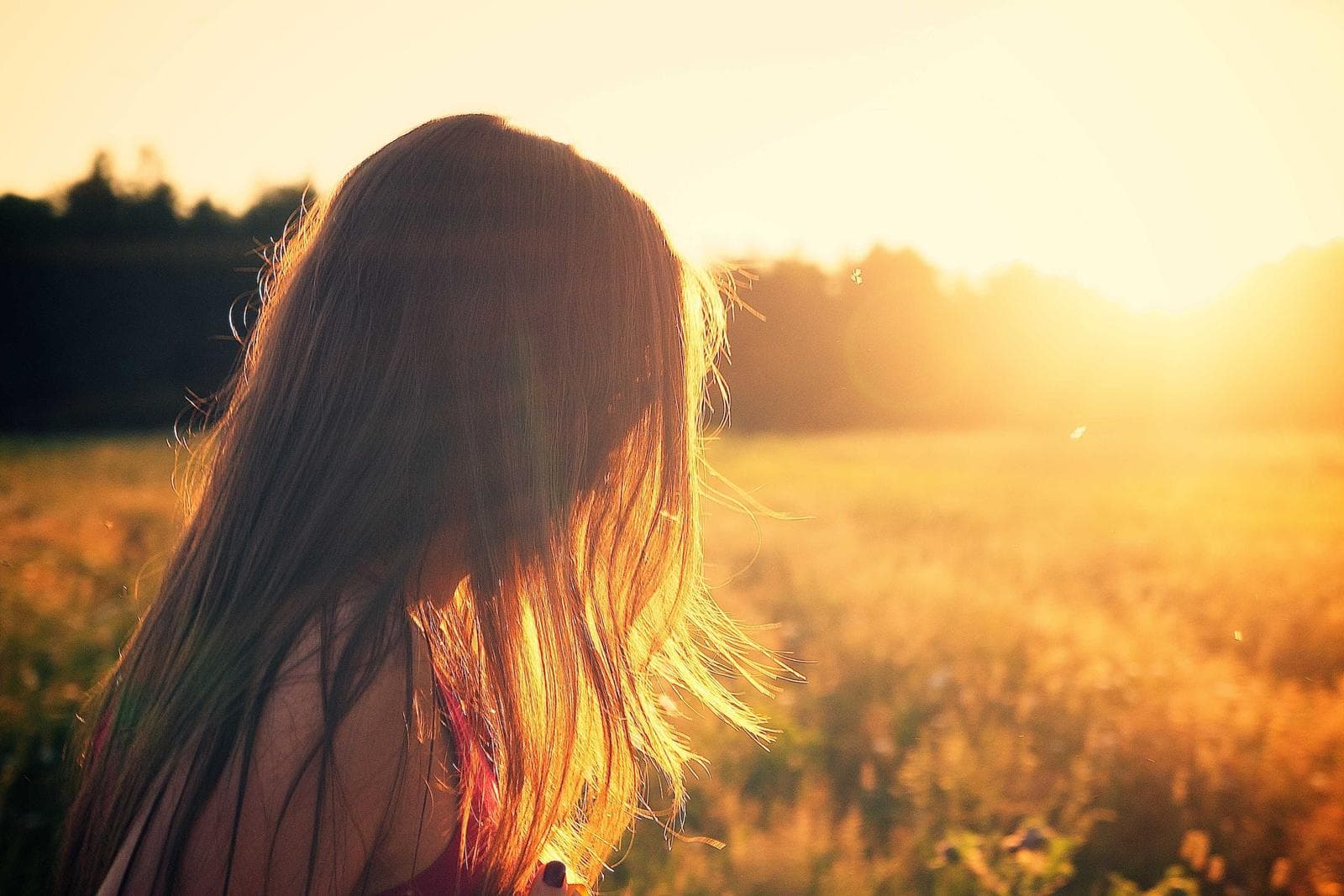 Person standing in a sunlit meadow at golden hour