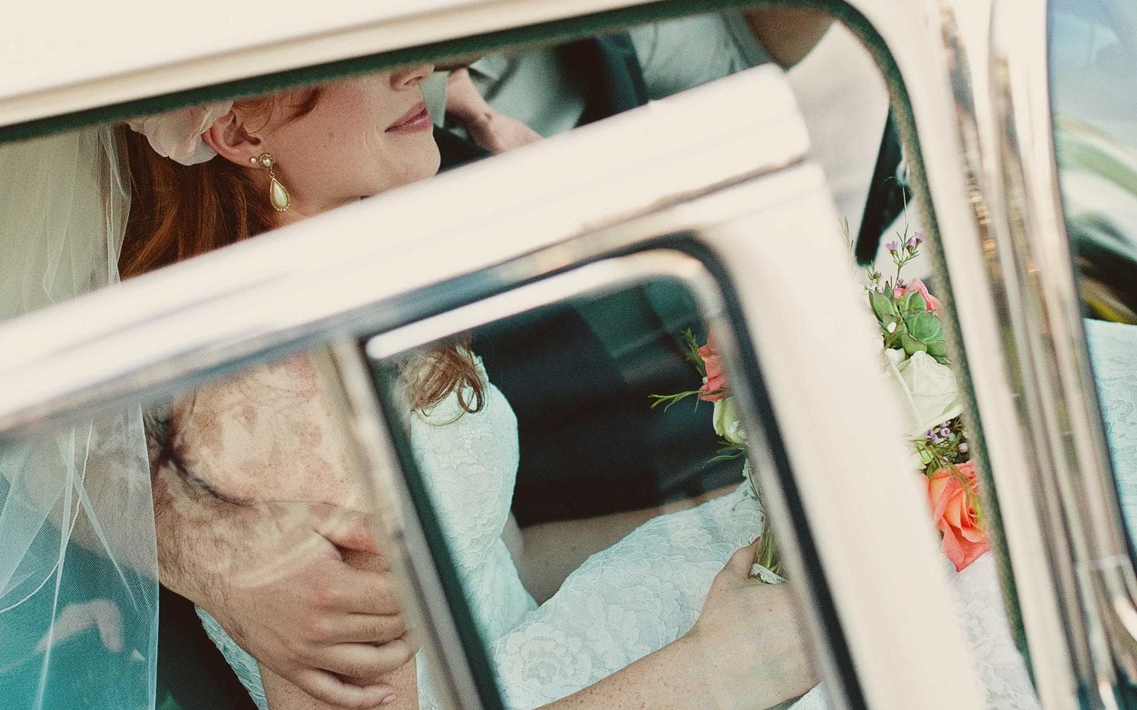 Bride seen through the windows of a vintage car